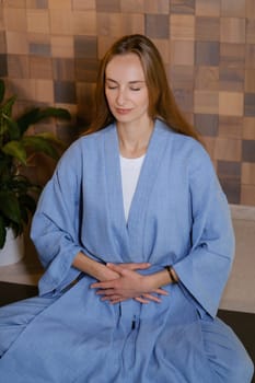 Girl in blue kimano practicing kundalini or qigong yoga in fitness gym . Spiritual energy, life force located at the base of the spine.