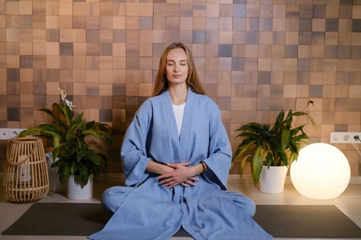 Girl in blue kimano practicing kundalini or qigong yoga in fitness gym . Spiritual energy, life force located at the base of the spine.