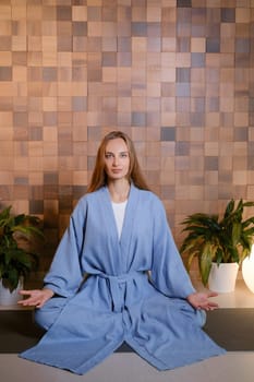 Girl in blue kimano practicing kundalini or qigong yoga in fitness gym . Spiritual energy, life force located at the base of the spine.