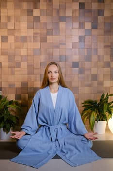 Yoga instructor in blue kimano at fitness gym . The girl does qigong yoga. The exercises are based on the movement of internal energy, the system of channels, energy centers, chakras.