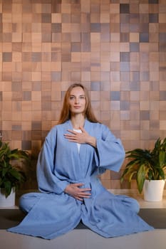 Girl in blue kimano practicing kundalini or qigong yoga in fitness gym . Spiritual energy, life force located at the base of the spine.