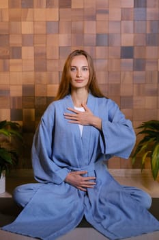 Girl in blue kimano practicing kundalini or qigong yoga in fitness gym . Spiritual energy, life force located at the base of the spine.