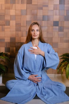 Yoga instructor in blue kimano at fitness gym . The girl does qigong yoga. The exercises are based on the movement of internal energy, the system of channels, energy centers, chakras.