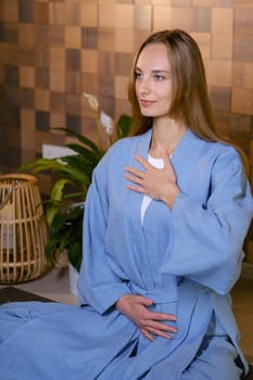 Girl in blue kimano practicing kundalini or qigong yoga in fitness gym . Spiritual energy, life force located at the base of the spine.