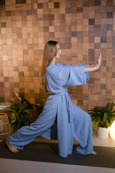 Girl in blue kimano practicing kundalini or qigong yoga in fitness gym . Spiritual energy, life force located at the base of the spine.
