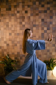 Yoga instructor in blue kimano at fitness gym . The girl does qigong yoga. The exercises are based on the movement of internal energy, the system of channels, energy centers, chakras.