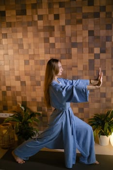Girl in blue kimano practicing kundalini or qigong yoga in fitness gym . Spiritual energy, life force located at the base of the spine.