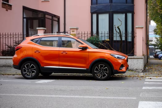 Cremona, Itally - October 6th 2024 Sleek and vibrant: a modern orange mg zs ev suv on a residential street, showcasing its stylish design and bold color