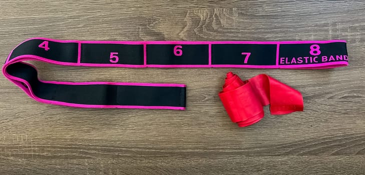 Elastic resistance band with numbered sections for versatile workout routines, placed on a wooden table. Ideal for strength training, stretching, and fitness exercises.
