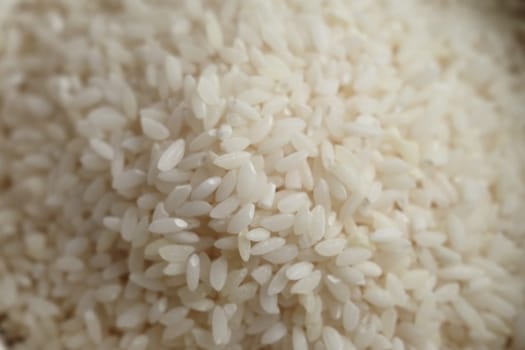 This is a closeup detailed view of many uncooked white rice grains closely stacked together