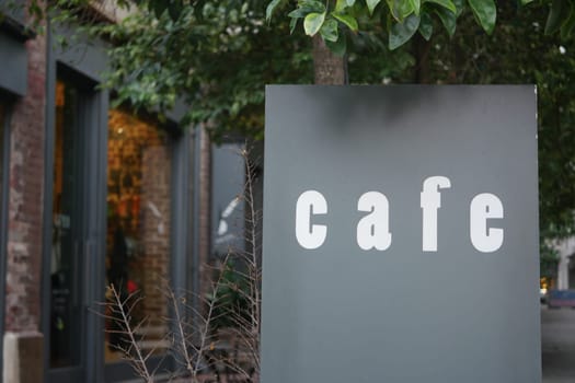 An elegantly designed cafe sign that warmly invites visitors surrounded by lush greenery