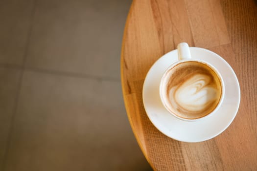 A beautifully crafted latte featuring stunning art displayed elegantly on a wooden table