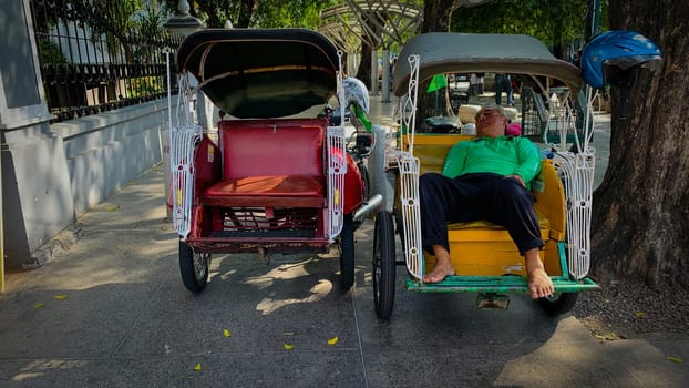 pedicab or rickshaw or locals calls it becak with a canopy is parked on a sunny street, reflecting a vibrant urban scene. The vehicle features a padded seat and unique design