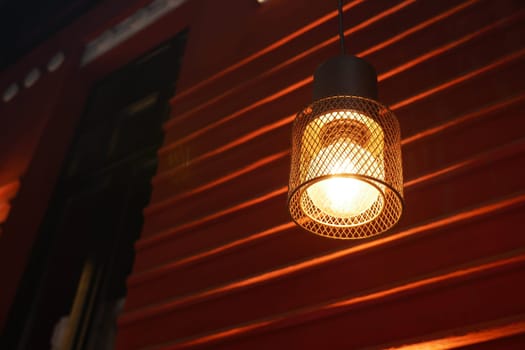 A contemporary hanging light fixture is casting a warm and inviting glow against a vibrant red wall