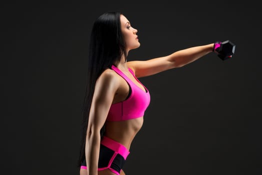 Slim brunette wearing pink top and shorts doing fitness with dumbells profile full-length view