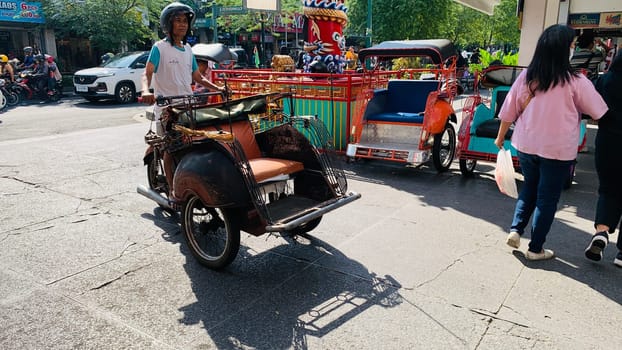pedicab or rickshaw or locals calls it becak with a canopy is parked on a sunny street, reflecting a vibrant urban scene. The vehicle features a padded seat and unique design