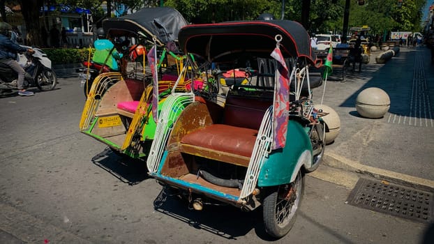pedicab or rickshaw or locals calls it becak with a canopy is parked on a sunny street, reflecting a vibrant urban scene. The vehicle features a padded seat and unique design