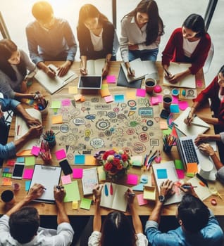 A group of people are sitting around a table with a large diagram on it. They are all working together on a project, with some people writing on the diagram and others looking at it