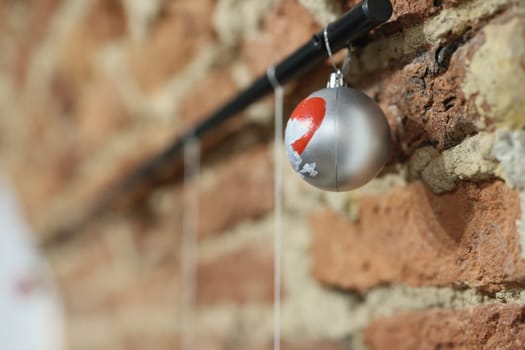 A silver ornament hangs gracefully from a rod, set against a textured brick wall, adding charm to the decor