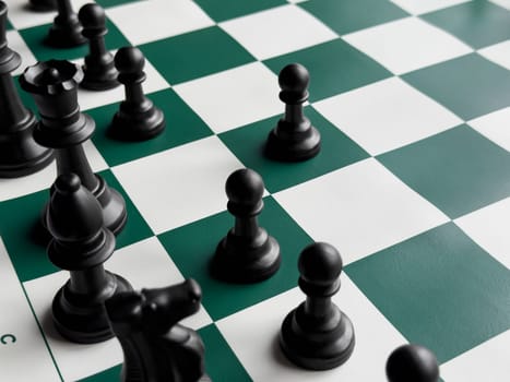 Strategic chess game on green and white board with black pieces.