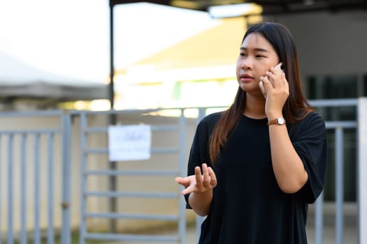Young asian woman talking on mobile phone in a bright, urban environment.