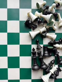 Scattered chess pieces on green and white board in a strategic match.
