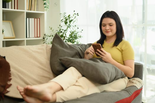 Young woman using her smartphone while relaxing on a couch in stylish living room decor.