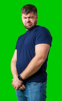 Man expressing confusion with crossed arms in front of a bright green background during a casual moment