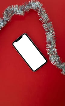 Mockup, smartphone and tinsel on a red background. Vertical background. Background for advertising.