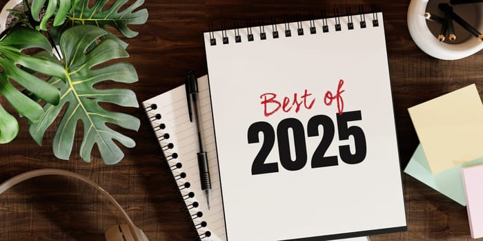 Best of 2025 journal lies on a wooden desk, surrounded by coffee, plants, and stationery, embodying a fresh and productive workspace.