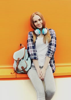 Fashion pretty smiling girl with headphones listens to music in city 