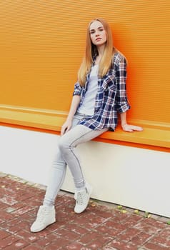 Fashion pretty woman in city over colorful orange background