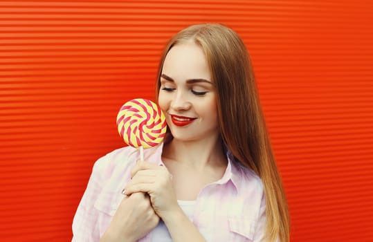 Portrait girl with sweet caramel lollipop over red background
