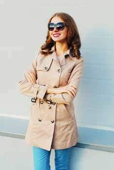 portrait pretty smiling woman wearing a coat and black sunglasses stands over grey background