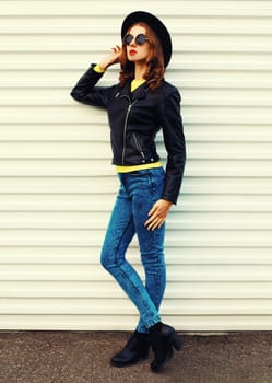Fashionable stylish young woman model full length posing in black jacket, hat on white background