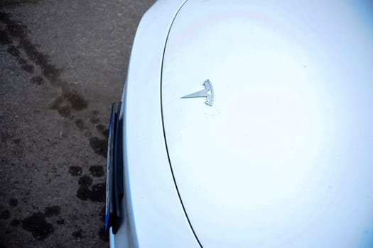 Cremona, Itally - October 6th 2024 Detailed shot of the tesla logo on the hood of a white model y, parked on a paved surface