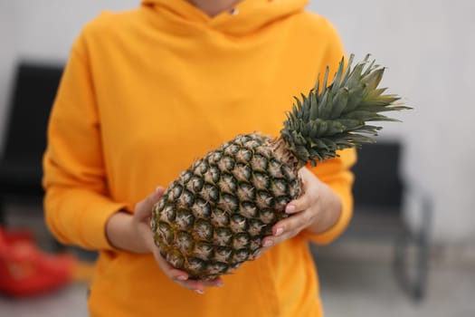 A person holding a ripe, juicy pineapple, proudly showcasing its vibrant colors and appealing health benefits