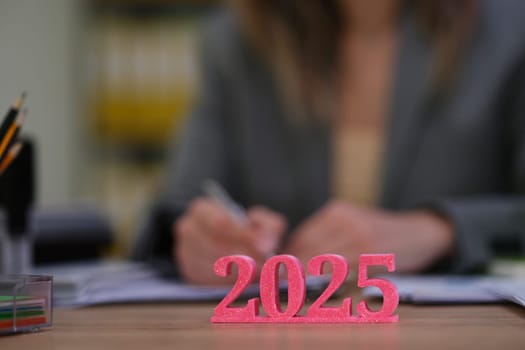 An ambitious professional meticulously planning for 2025, with vibrant figures displayed on their desk