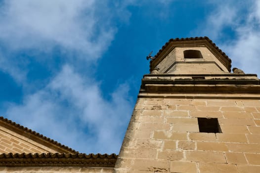 A historic stone tower extends into a vibrant blue sky, offering a contrasting view of architecture and nature.