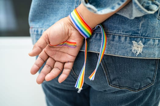 Asian lady wearing rainbow flag wristbands, symbol of LGBT pride month celebrate annual in June social of gay, lesbian, bisexual, transgender, human rights.