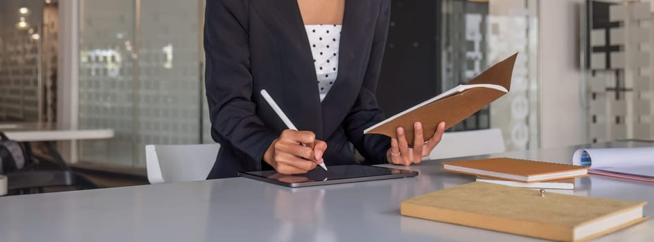 young Asian businesswoman taking notes using a laptop at the modern office..