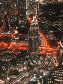 This captivating image captures the essence of a bustling cityscape at night. The heart of the city is a towering skyscraper, glowing with a myriad of lights, standing tall amidst the surrounding buildings. High quality photo