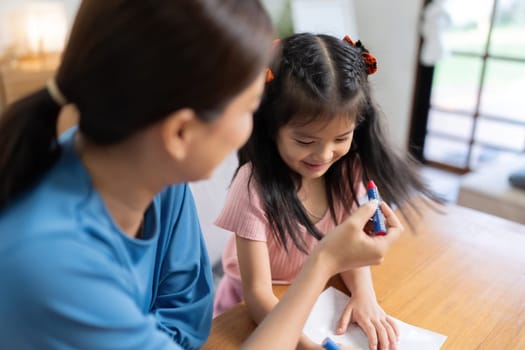 Happy family mother and daughter study or draw together at home in living room.