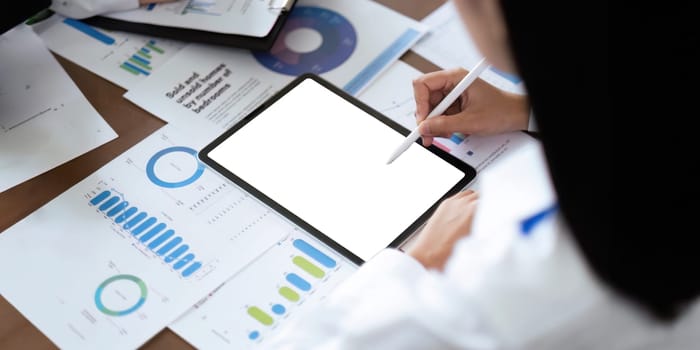 Blank screen mockup of man hand working on tablet work while sitting at the table, mockup blank screen for graph finance display or graphic design workspace.