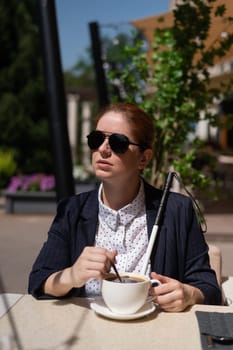 Blind woman in business suit drinking coffee in outdoor cafe