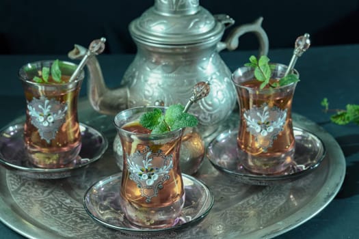 close-up of a traditional Moorish mint tea service, with decorated glassware and silver teapot and silver sugar bowl