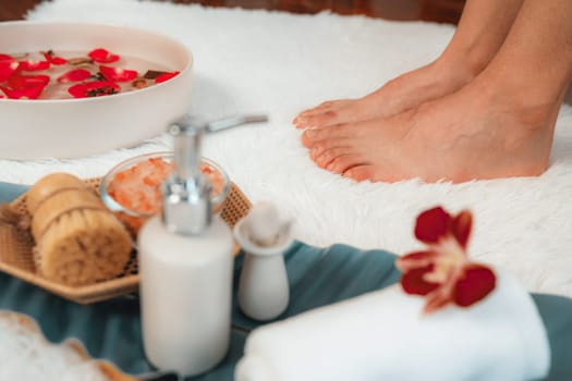 Woman indulges in blissful foot massage at luxurious spa salon while masseur give reflexology therapy in gentle day light ambiance resort or hotel foot spa. Quiescent