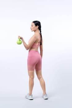 Vigorous energetic woman doing kettlebell weight lifting exercise on isolated background. Young athletic asian woman strength and endurance training session as body workout routine.