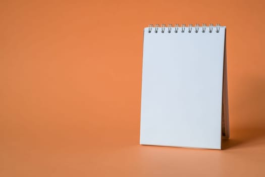 Opened notepad on orange background. Composition of writing to-dos for the day. The notebook lies on a plain background with space for writing.