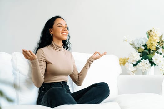 Young African American woman practice crucial mindful meditation at home living room for improving mental health strength and peaceful beautiful living